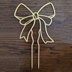 Gold bow trellis lying flat on a wood surface