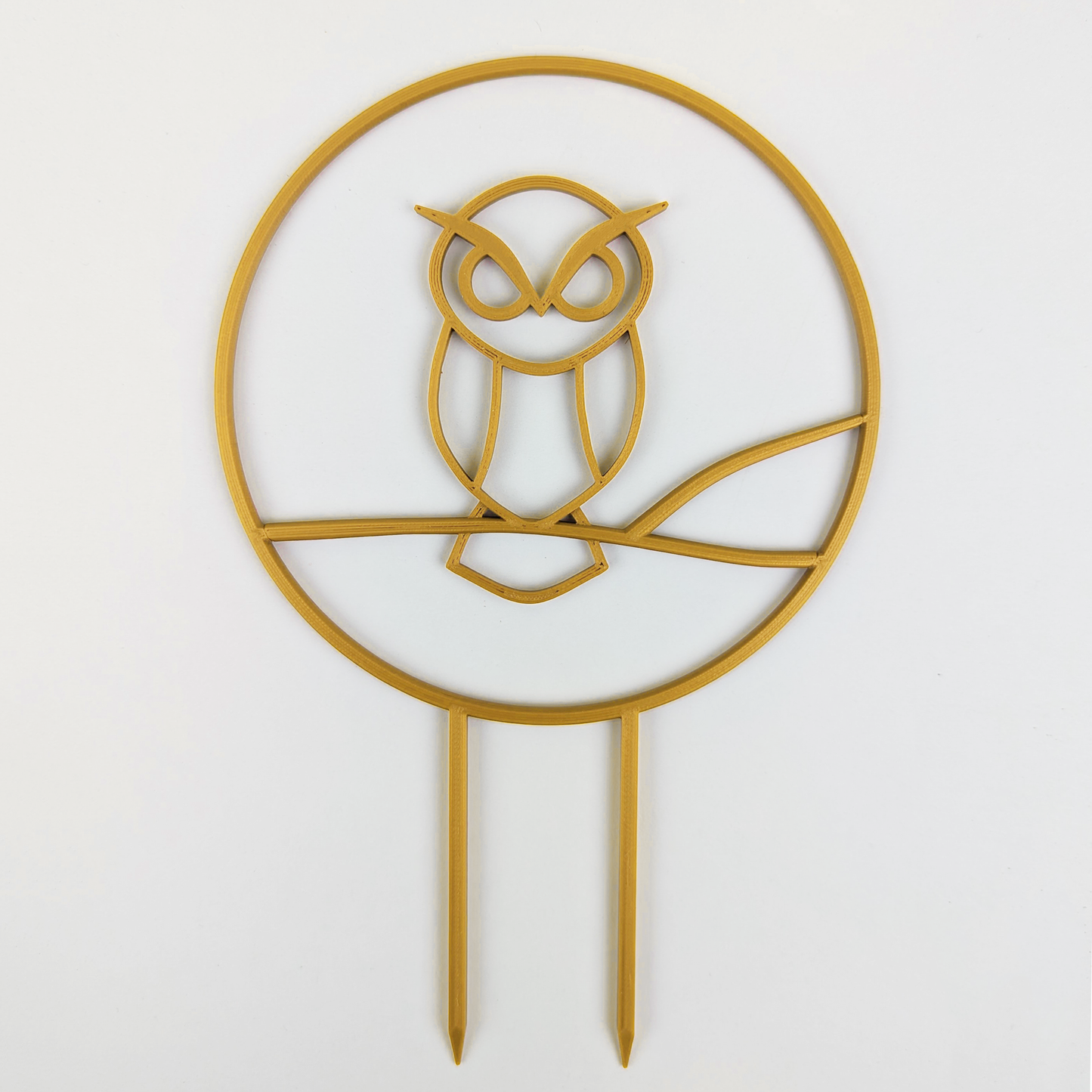 A circular trellis with an owl design in the middle. It is in the color gold.