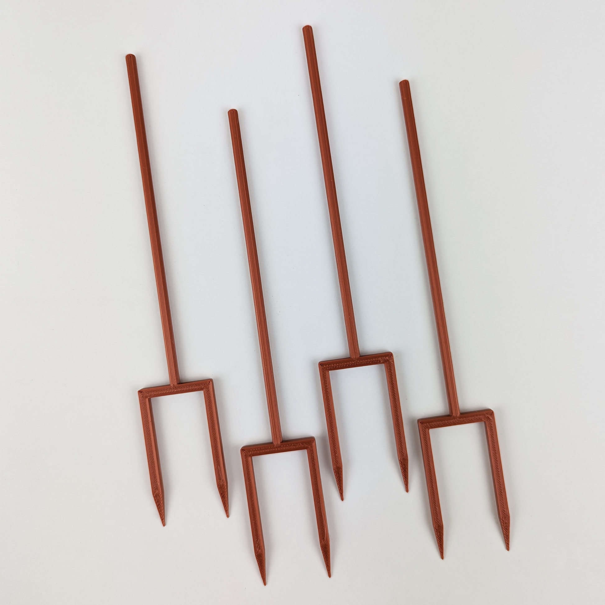 4 double legged stakes in the color copper