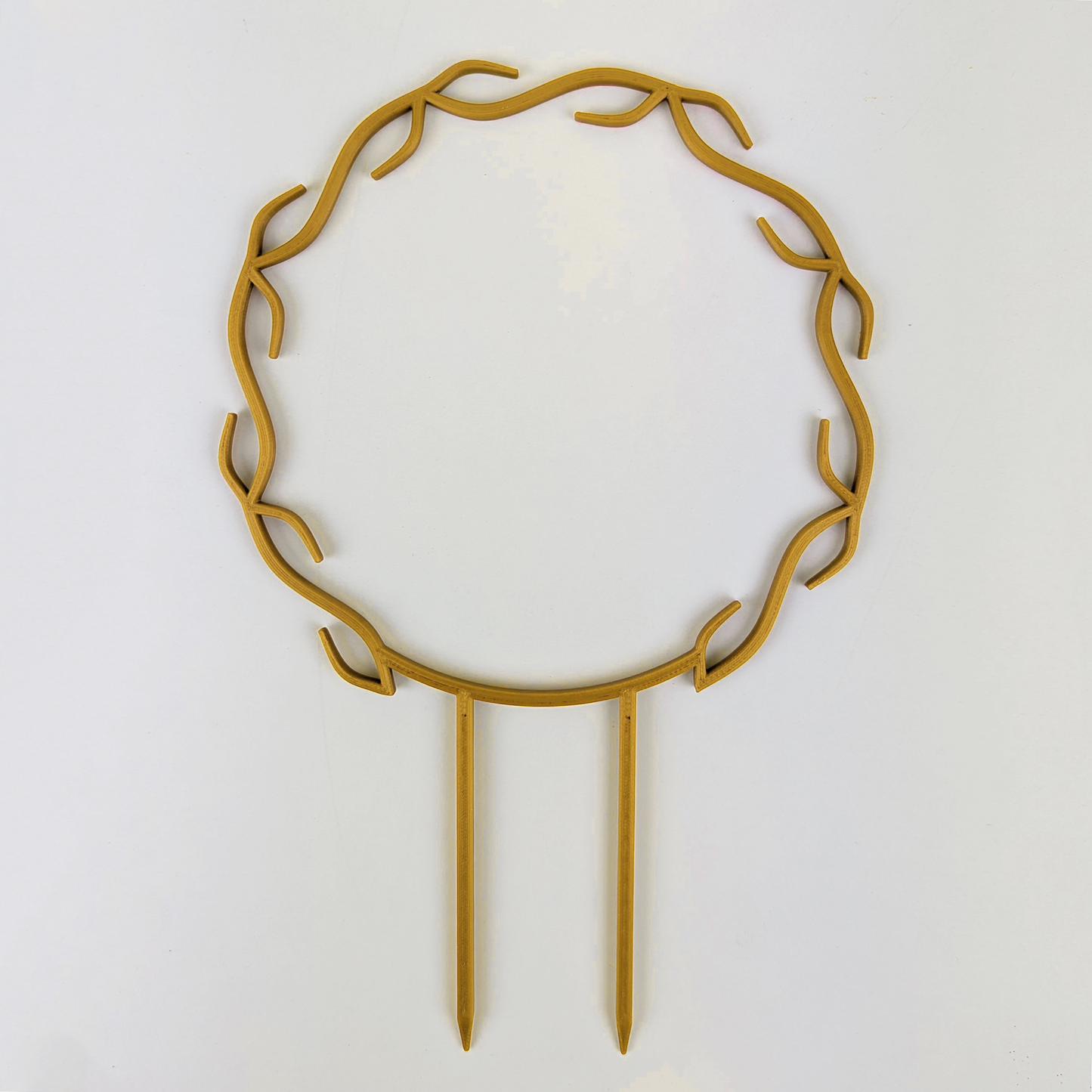 A wreath trellis. It has little hooks that go around in a circle, almost looking like a wreath. It is in gold colour against a white background.