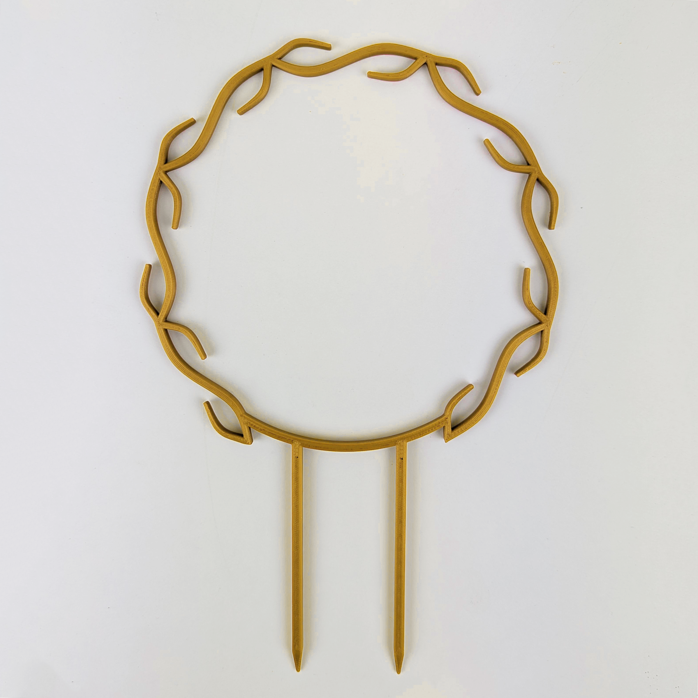 A wreath trellis. It has little hooks that go around in a circle, almost looking like a wreath. It is in gold colour against a white background.