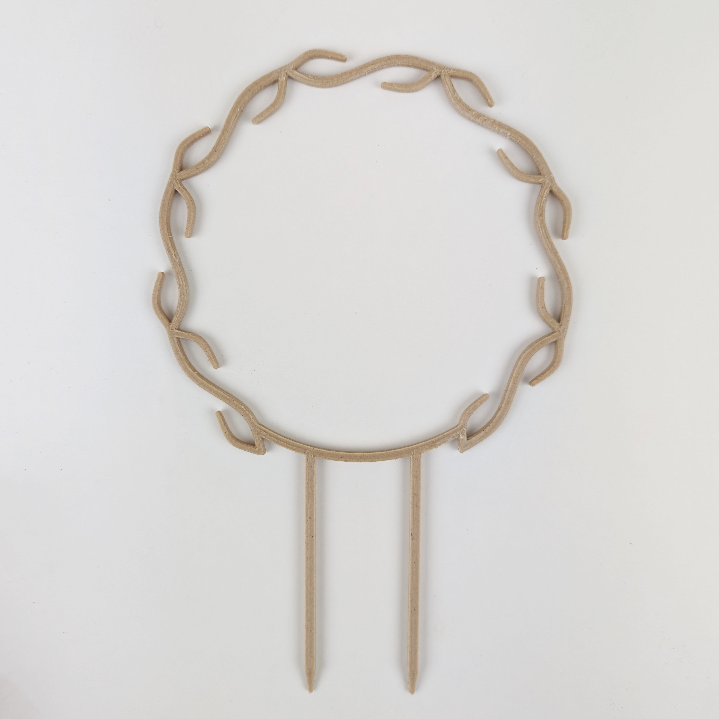 A wreath trellis. It has little hooks that go around in a circle, almost looking like a wreath. It is in wood colour against a white background.